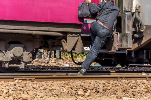 People step up to railway train on the railroad tracks in Bangkok station. Many people in Thailand popular travel by train because it is cheaper.