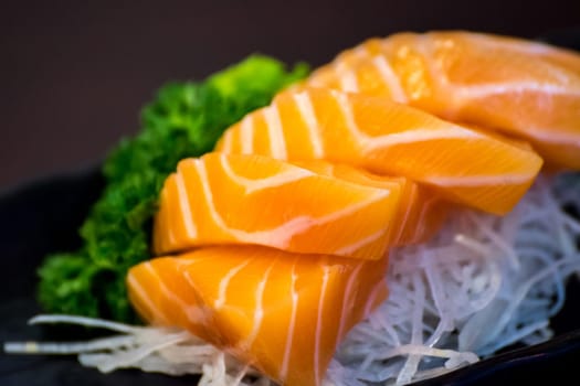 Japanese food delicacy consisting sashimi salmon of very fresh raw salmon fish sliced into thin pieces serving with radish sliced in japanese restaurant