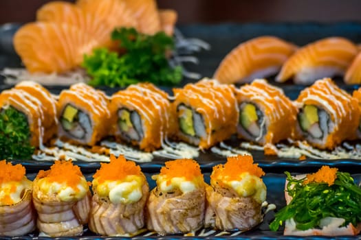 Japanese food in set different types of sushi with seaweed salad and gari (ginger) is a healthy food at the upper right of the serving board in japanese restaurant