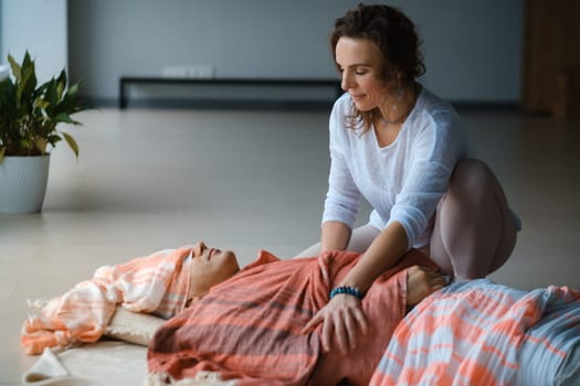 A person receives a calming head massage while lying on a soft surface, surrounded by warm colors. The atmosphere is tranquil and inviting, promoting relaxation and a sense of well-being during the session.