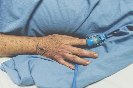 Patient in the hospital with pulse gauge for heartbeat measuring and blood pressure on a patient elderly finger