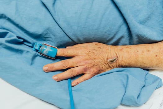 Patient in the hospital with pulse gauge for heartbeat measuring and blood pressure on a patient elderly finger