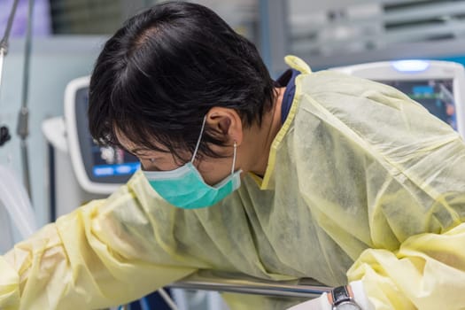 Asian women 40s years old is a patient relative taking care of the CRE. or VRE. infected elder patient 80s years old on patient bed in intensive care unit (ICU.) room at hospital.