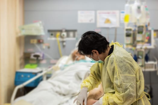 Asian women 40s years old is a patient relative taking care of the CRE. or VRE. infected elder patient 80s years old on patient bed in intensive care unit (ICU.) room at hospital.