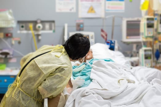 Asian women 40s years old is a patient relative taking care of the CRE. or VRE. infected elder patient 80s years old on patient bed in intensive care unit (ICU.) room at hospital.