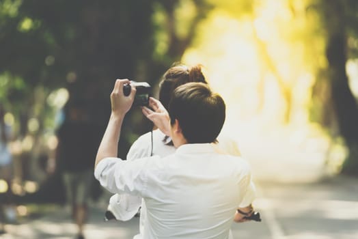 Couple lovers cycling bicycle by girlfriend and boyfriend use digital camera take a photo having romantic love in a park