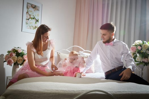 A couple enjoys a tender moment while their baby girl plays with a toy in a warm, inviting space filled with soft lighting.