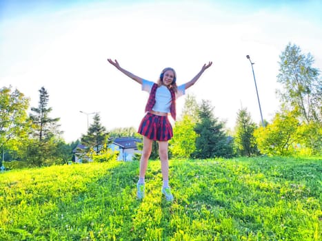 A cheerful girl stands on a grassy hill, arms raised with excitement, surrounded by trees and a bright blue sky.