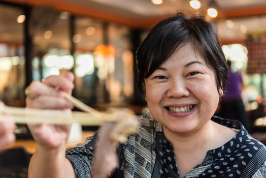 Asian woman plump body holding a raw meat beef and pork (barbeque, bbq) a food cooking on wagyu grill in BBQ. yakiniku grill buffet restaurant