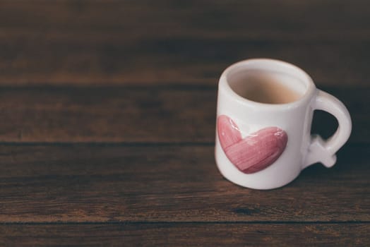 Ceramic white cup with heart shape sweet pink color on wooden floor with copy space in Valentine's Day, Wedding or Romantic Love concept