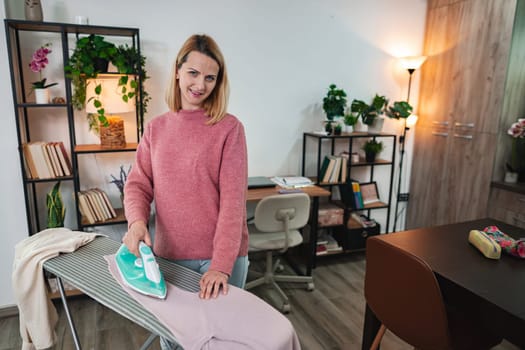 A cheerful woman steams clothes in a bright, inviting space.