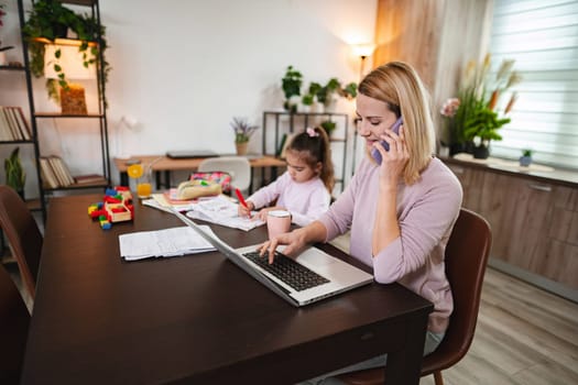 A dedicated mother multitasks with her daughter while managing tasks.