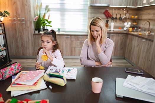 A girl drinks juice while her mother thinks about their challenges.