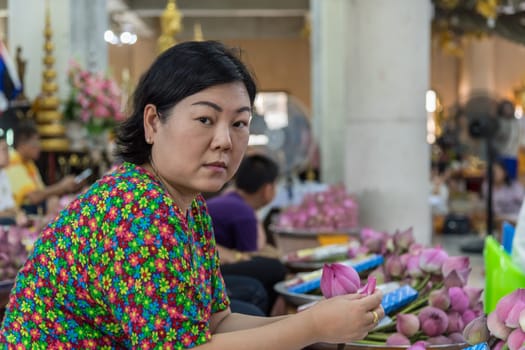 Thai buddhism people in buddhist pray for benefaction worship by incense and garland to Buddha or spirit-house at shrine or Thai temple (Wat Thai)