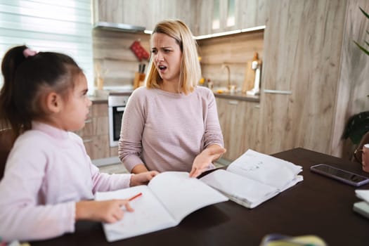 Frustrated mother guides her daughter through assignments at home.
