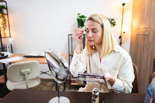 A woman enhances her beauty routine in a stylish workspace.