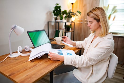 Person meticulously reviews charts and reports in a warm workspace.