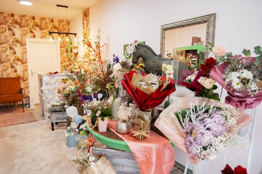 Inside a vibrant flower shop, a variety of stunning floral arrangements in rich hues create an inviting atmosphere. Charming decor and soft lighting enhance the cheerful vibe of the space.