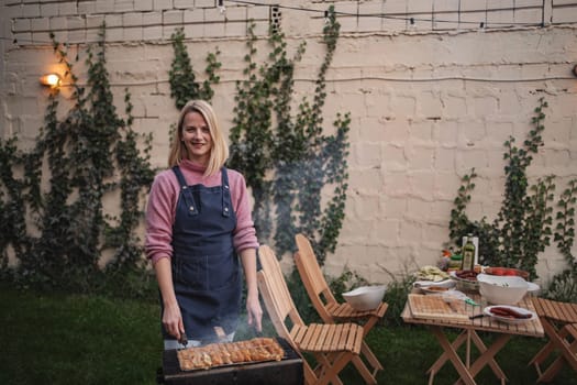 A woman grills delicious food in a cozy backyard, surrounded by nature.