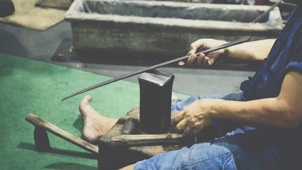 Blacksmith or professional knife hit a knife or sword for show how to make traditional sword from iron.