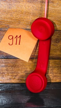 Writing 911 on memo post reminder.  sticky paper with text 911 and landline phone.