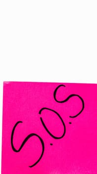 SOS handwriting text close up isolated on pink paper with copy space. Writing text on memo post reminder