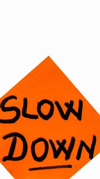 Slow down handwriting text close up isolated on yellow paper with copy space.