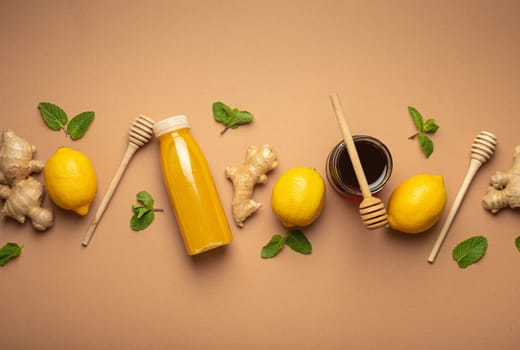 Composition with detox drink, lemons, mint, ginger, honey in glass jar, honey wooden dippers top view. Food for immunity stimulation and against flu. Healthy natural remedies to boost immune system.