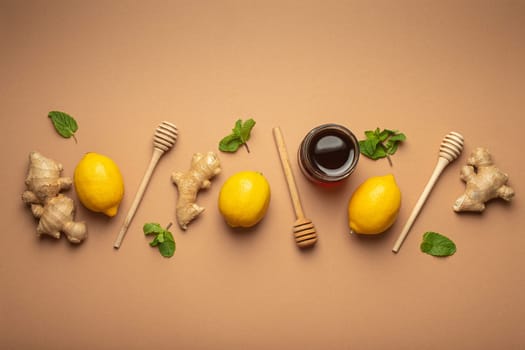 Composition with lemons, mint, ginger, honey in glass jar and honey wooden dippers top view. Food for immunity stimulation and against seasonal flu. Healthy natural remedies to boost immune system.