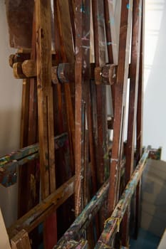 Cropped image of wooden easels smeared with oil paints in a art workshop. Painting tools. Fine art. Creative hobby and occupation