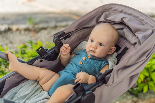 A cute baby, dressed in soft muslin clothes, sits contentedly in a stroller, basking in comfort and coziness on a sunny day.