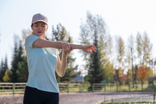 A young beautiful woman in sportswear plays sports at a local stadium. Exercise, jog and exercise at the beginning of the day. Healthy and active lifestyle.