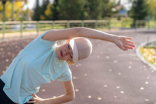 A young beautiful woman in sportswear plays sports at a local stadium. Exercise, jog and exercise at the beginning of the day. Healthy and active lifestyle.