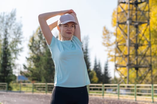 A young beautiful woman in sportswear plays sports at a local stadium. Exercise, jog and exercise at the beginning of the day. Healthy and active lifestyle.