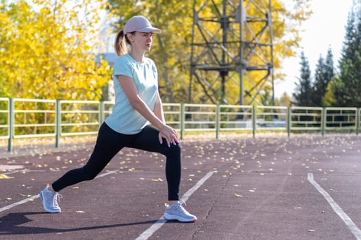 A young beautiful woman in sportswear plays sports at a local stadium. Exercise, jog and exercise at the beginning of the day. Healthy and active lifestyle.