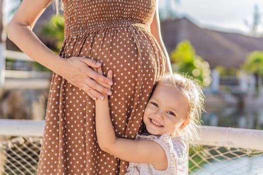 A heartwarming moment captured as a daughter lovingly embraces her mother's pregnant belly, sharing in the excitement and anticipation of a new family member.