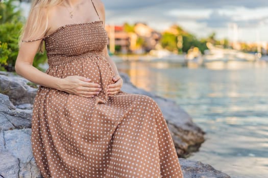 Pregnant woman hugging her tummy standing outdoors surrounded by nature. Pregnancy, expectation, motherhood concept.