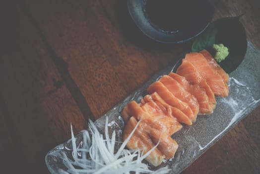 Japanese food delicacy consisting sashimi salmon of very fresh raw salmon fish sliced into thin pieces serving with radish sliced in japanese restaurant