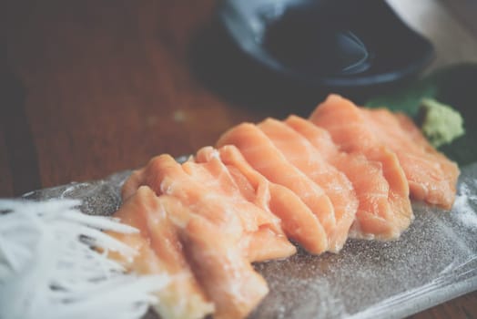 Japanese food delicacy consisting sashimi salmon of very fresh raw salmon fish sliced into thin pieces serving with radish sliced in japanese restaurant
