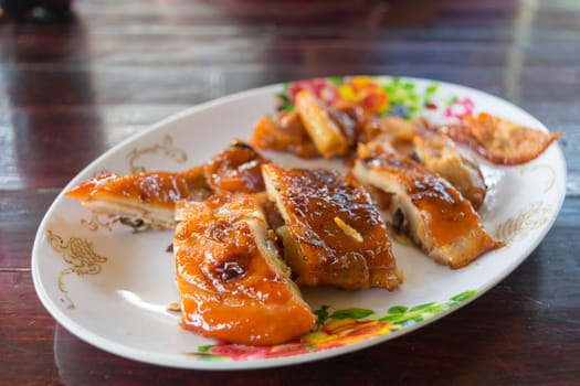 Grilled chicken in dish on wood table