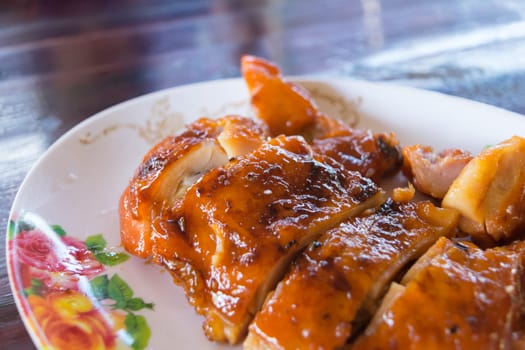 Grilled chicken in dish on wood table