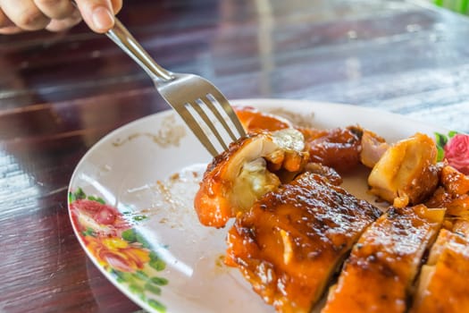 Grilled chicken sauce is a Thai barbeque food by chicken and sauce cooking on charcoal with flames at Thai street food market