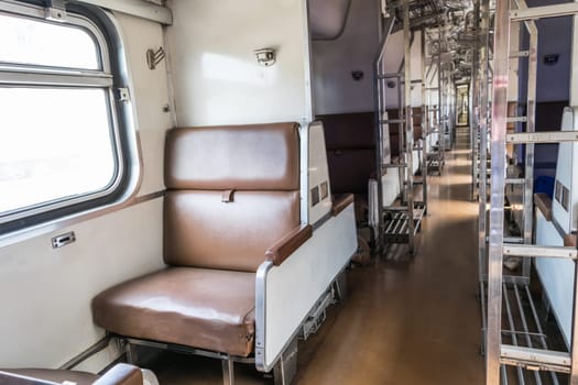 Inside of old public Thai railway train cabin with seats, handrails, fan and interior in vintage style service for passenger transport