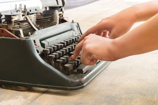 Vintage typewriter and human hand on a wood table