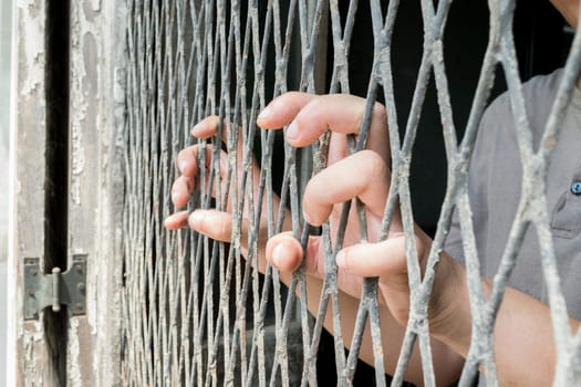 Hands of the woman on a steel lattice close up