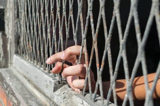Hands of the woman on a steel lattice close up