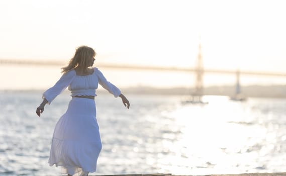 Young woman is happily dancing on the pier at sunset with the golden gate bridge in the background