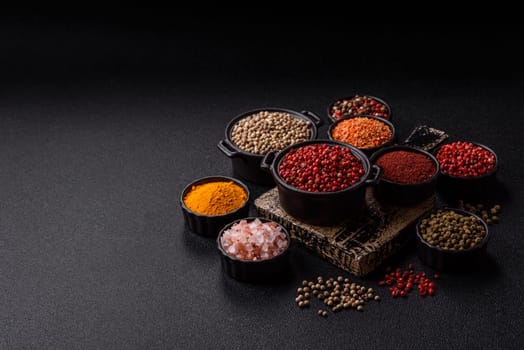 Variations of spices, allspice, turmeric, paprika, salt in ceramic bowls on a dark concrete background