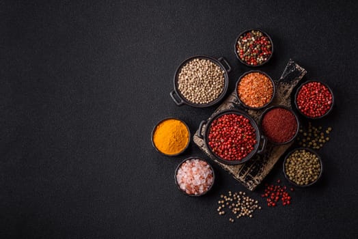 Variations of spices, allspice, turmeric, paprika, salt in ceramic bowls on a dark concrete background