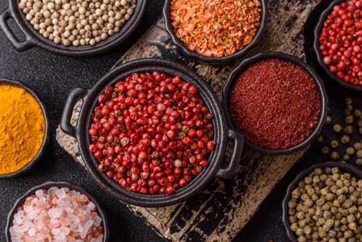 Variations of spices, allspice, turmeric, paprika, salt in ceramic bowls on a dark concrete background